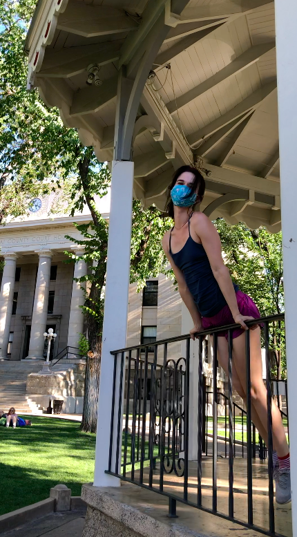 girl posing in front of courthouse plaza with green tank top and purple shorts