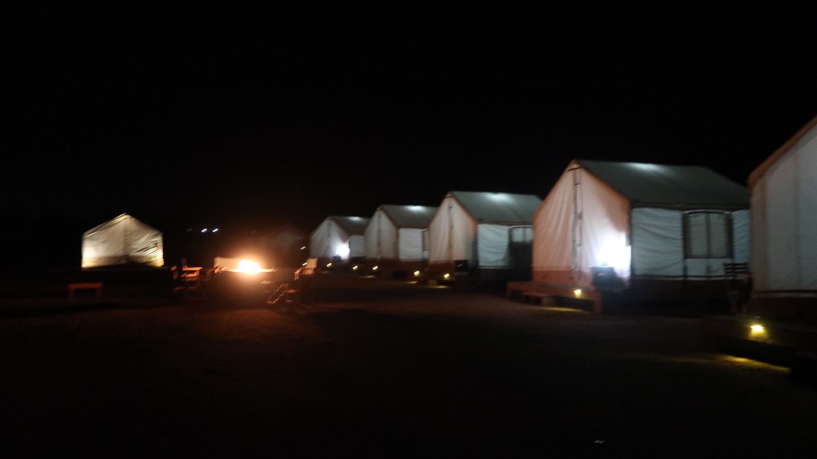 White tents for glamping with fire pits in front