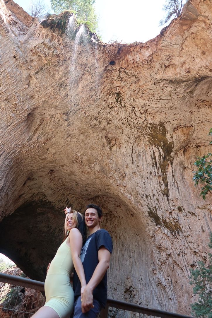 A young man and young woman standing in front of the Tonto Natural Bridge in Pine Arizona