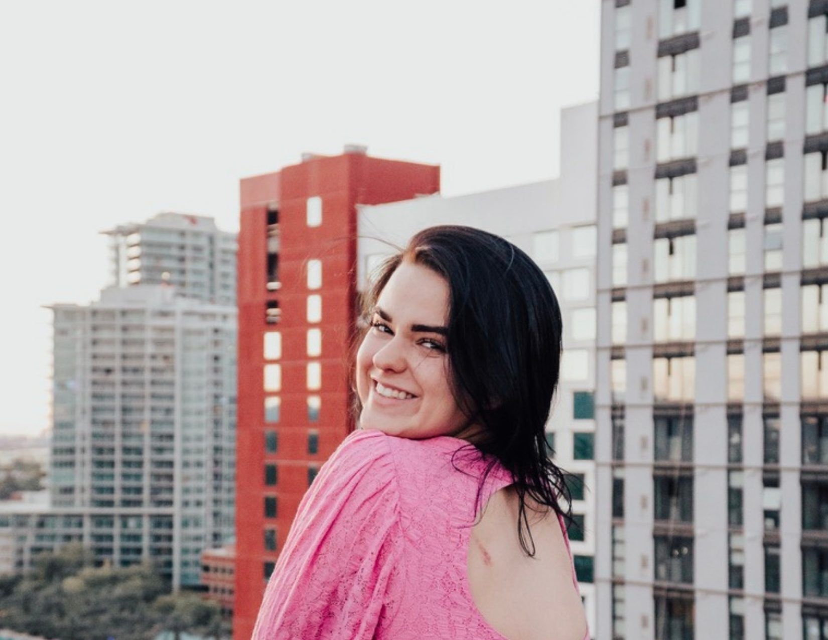 Lacy Cain posing in front of buildings at Alibi Rooftop Bar in Tempe Arizona