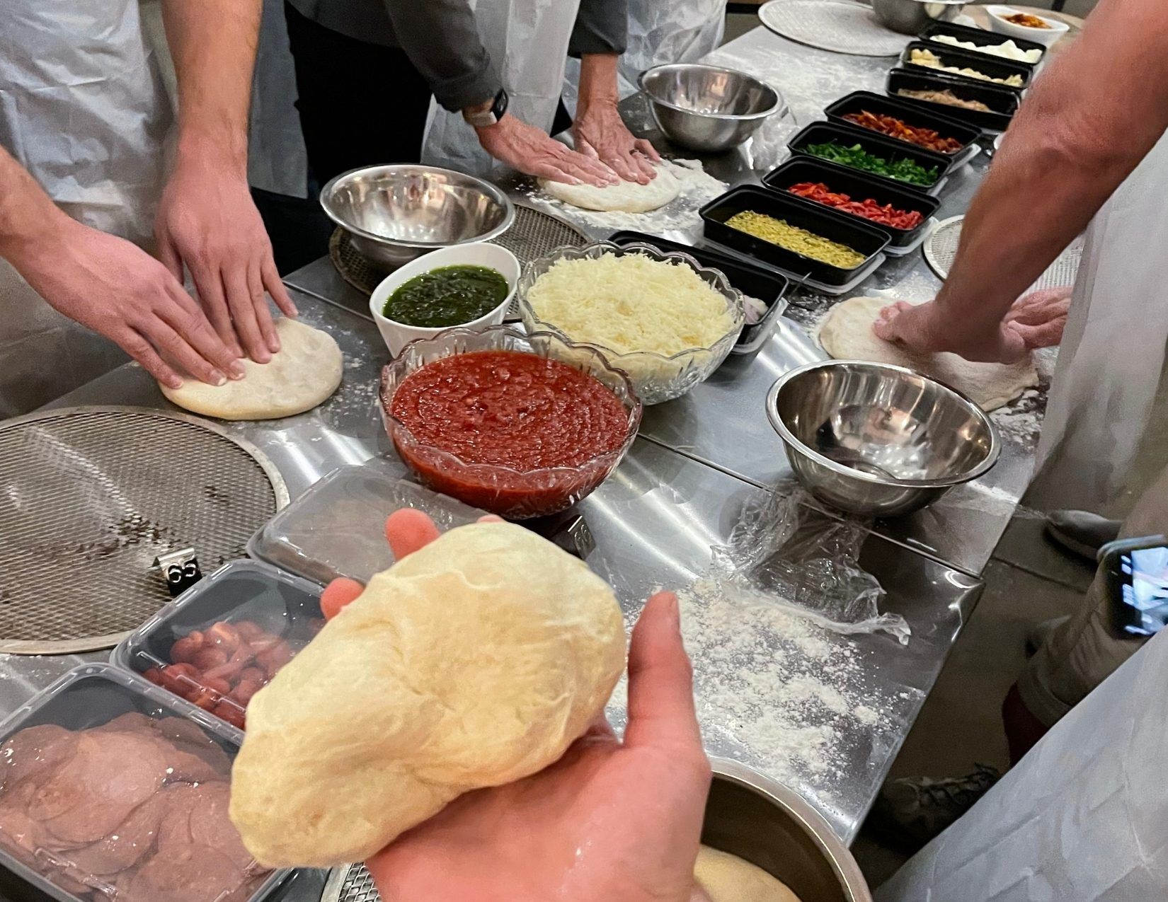 Hands working Pizza dough with ingredients on the table on the Fresh Foodie Trail in Mesa Arizona