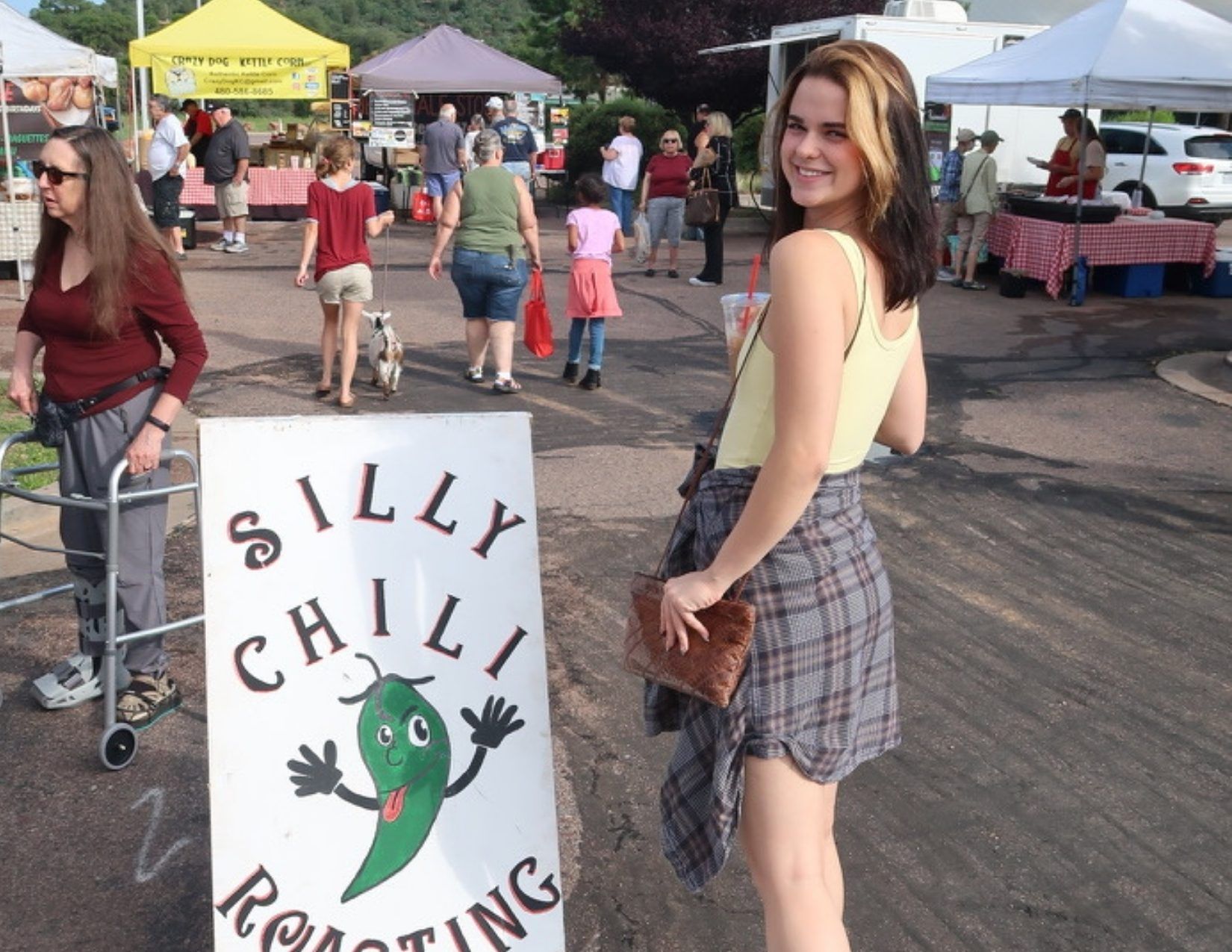 Girl standing in front of Silly Chili Roasting sign Payson Farmers Market, Arizona