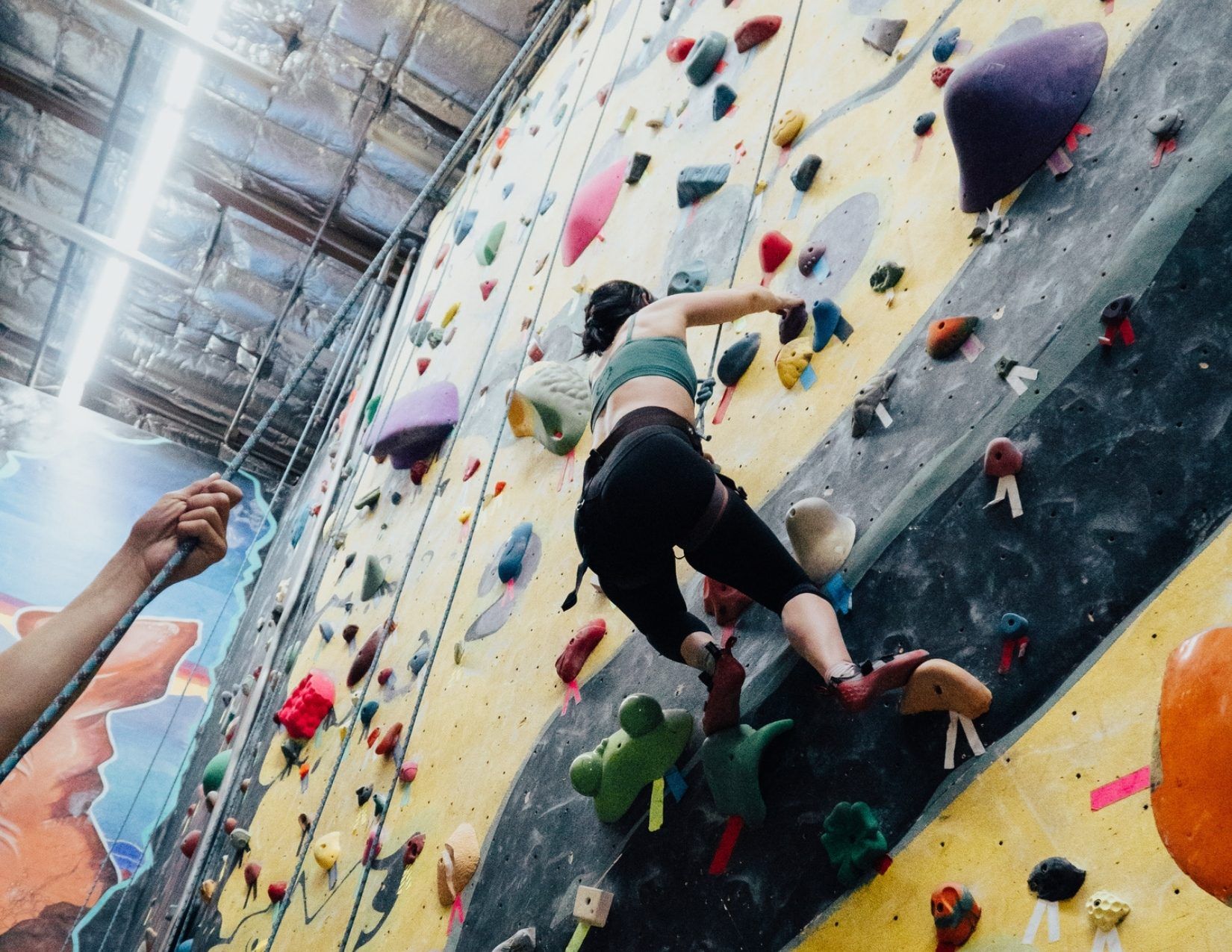 Lacy Cain climbing a rock wall at Phoenix Rock Gym in Tempe Arizona