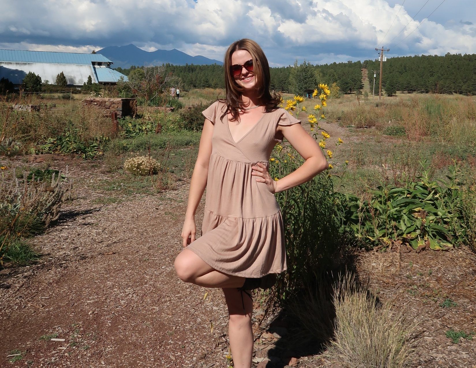 a young woman in a tan dress posing at the Arboretum in Flagstaff, Arizona