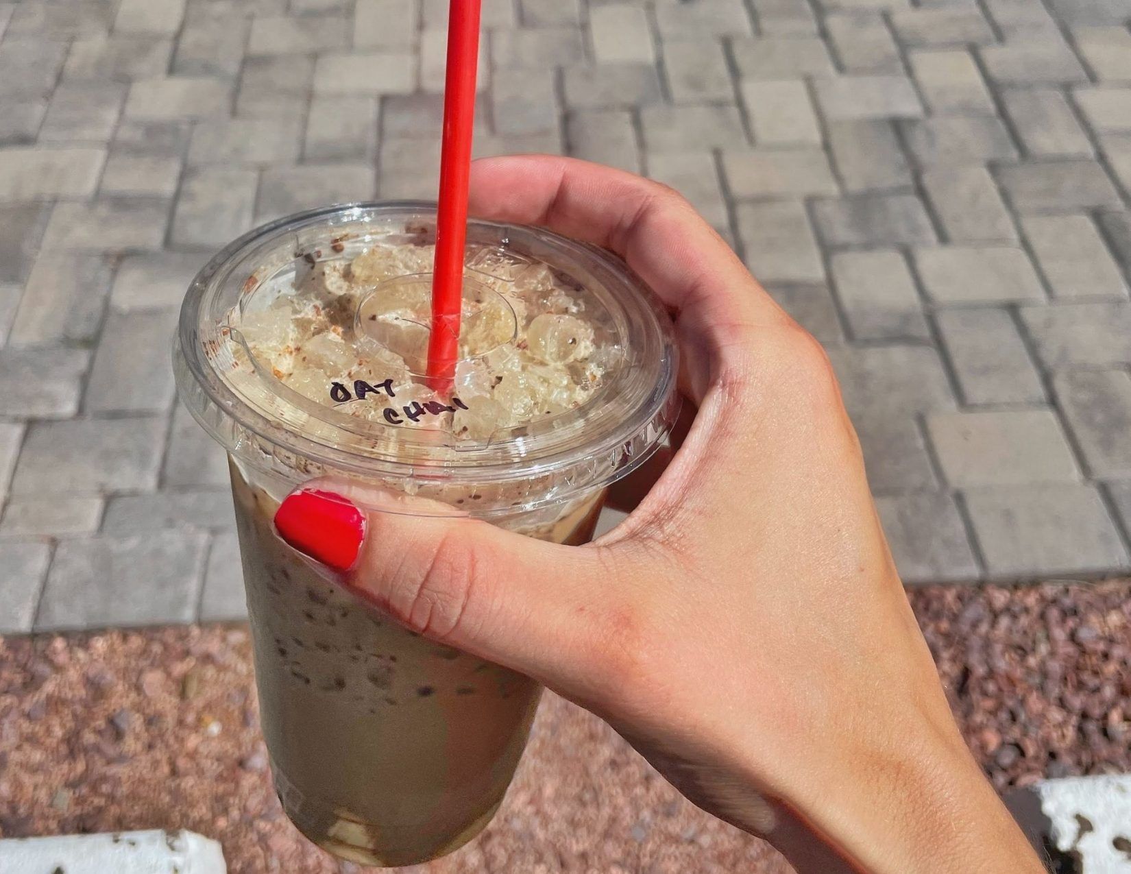 A hand holding an iced chai latte from a coffee shop in Strawberry, Arizona