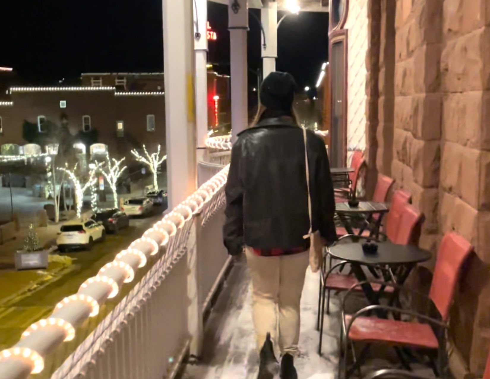 A young woman dressed in warm clothes walking on a wrap-around balcony during Christmas time in downtown Flagstaff, Arizona.