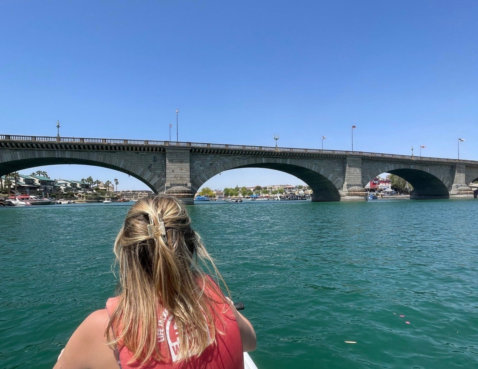 iconic bridge over Lake Havasu in Arizona, blue waters, girl with blonde hair on a jet ski