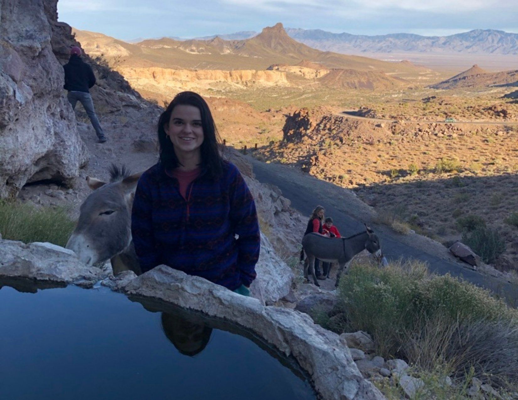 Young woman posing with Wild Burro and natural spring with the Arizona wilderness in the distance