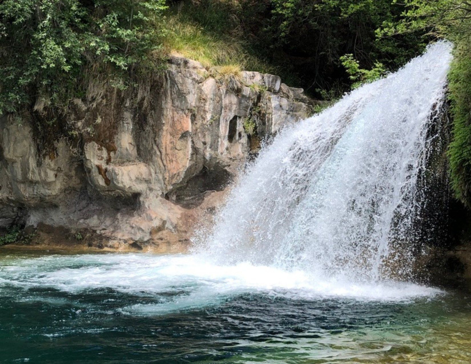 Surging waterfall with blue water and luscious green foliage in Fossil Creek in Pine Arizona