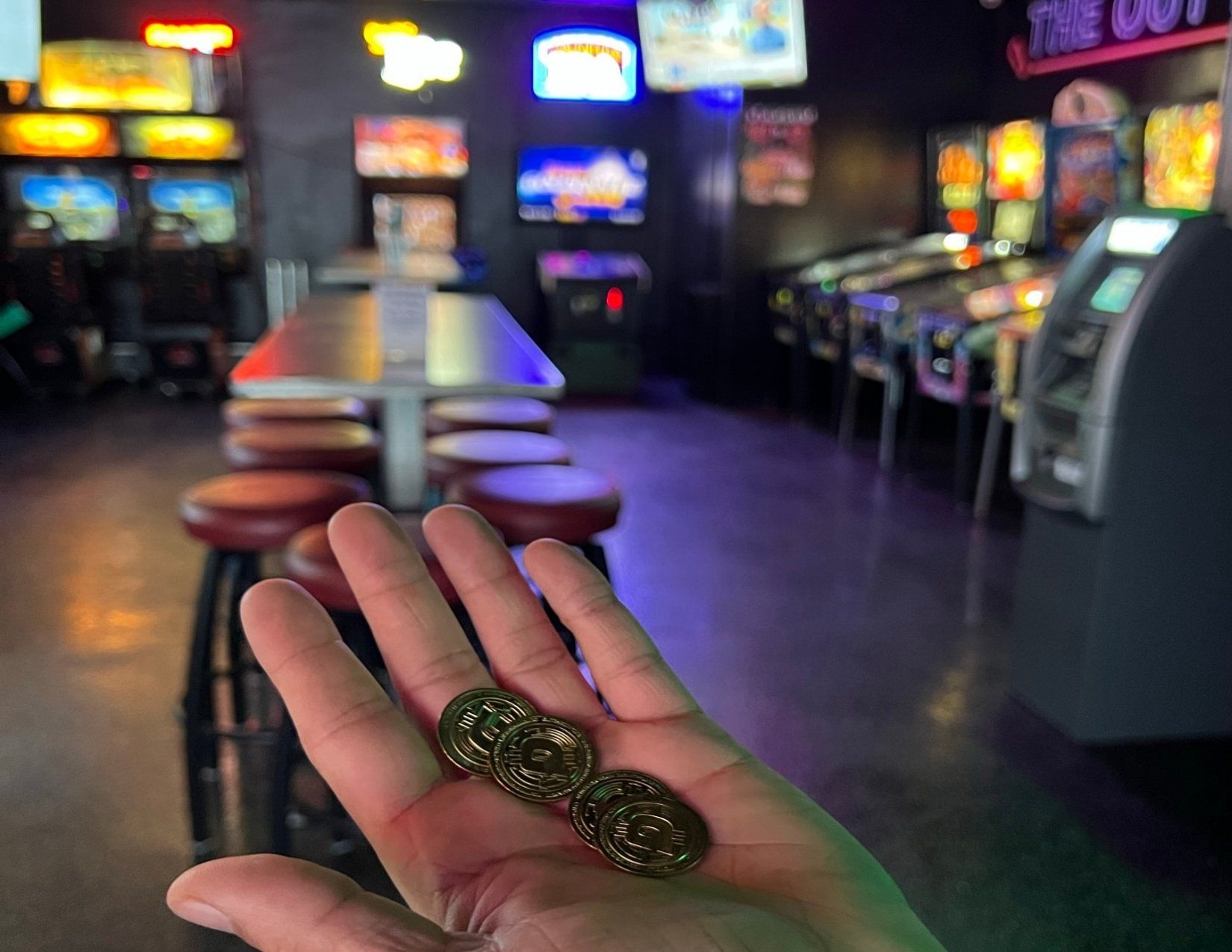 a hand holding coins to use for arcade games at an arcade bar in Lake Havasu City, Arizona