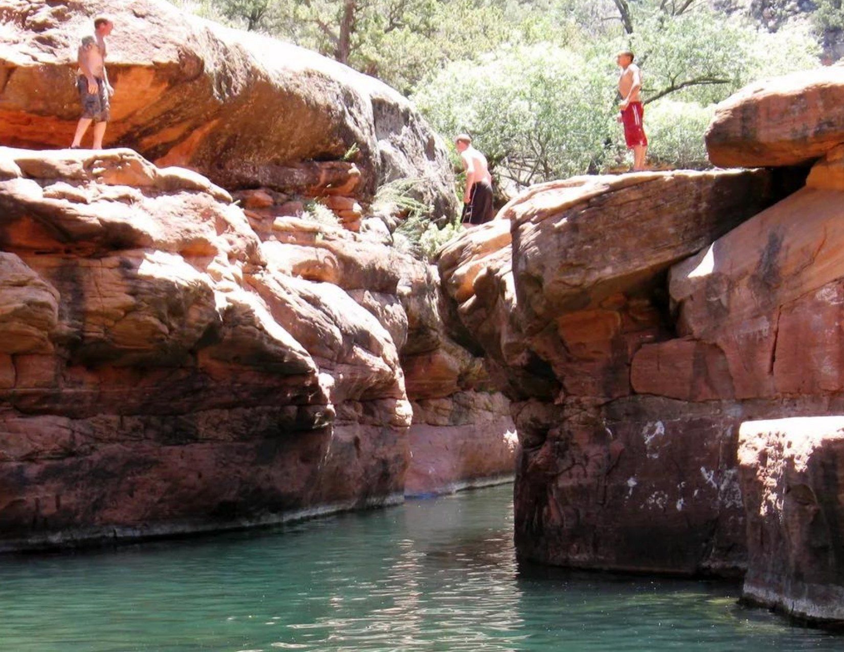 3 men on top of rocks over the water at The Crack at Wet Beaver Creek in Sedona Arizona