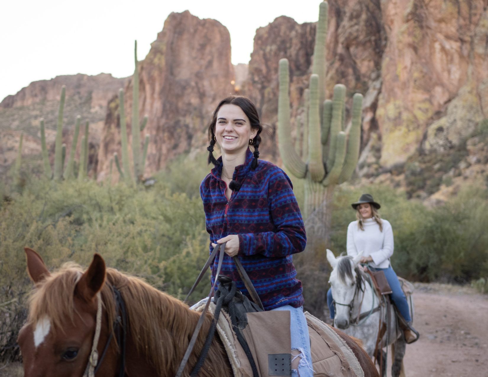 girl on a brown horse with another woman on a white horse in the background at Saguaro Lake Ranch Stables