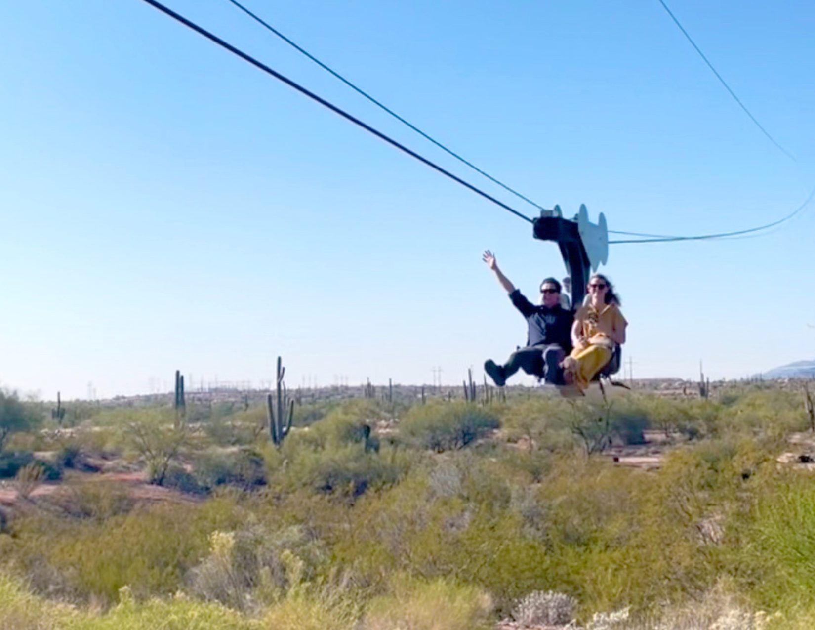 man and woman riding on a zip line at the Goldfield Ghost Town in Mesa Arizona