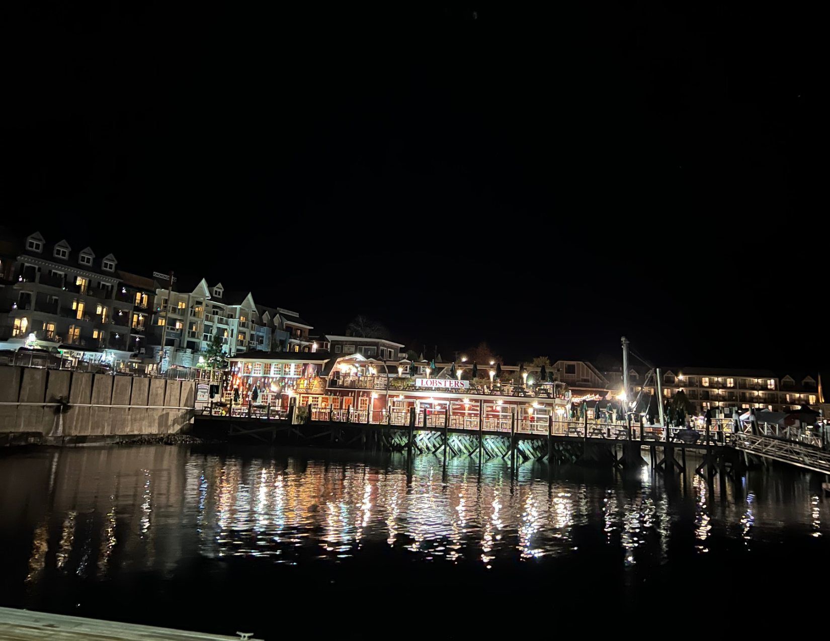 View of Bar Harbor at night, with lights from the businesses reflecting on the water.