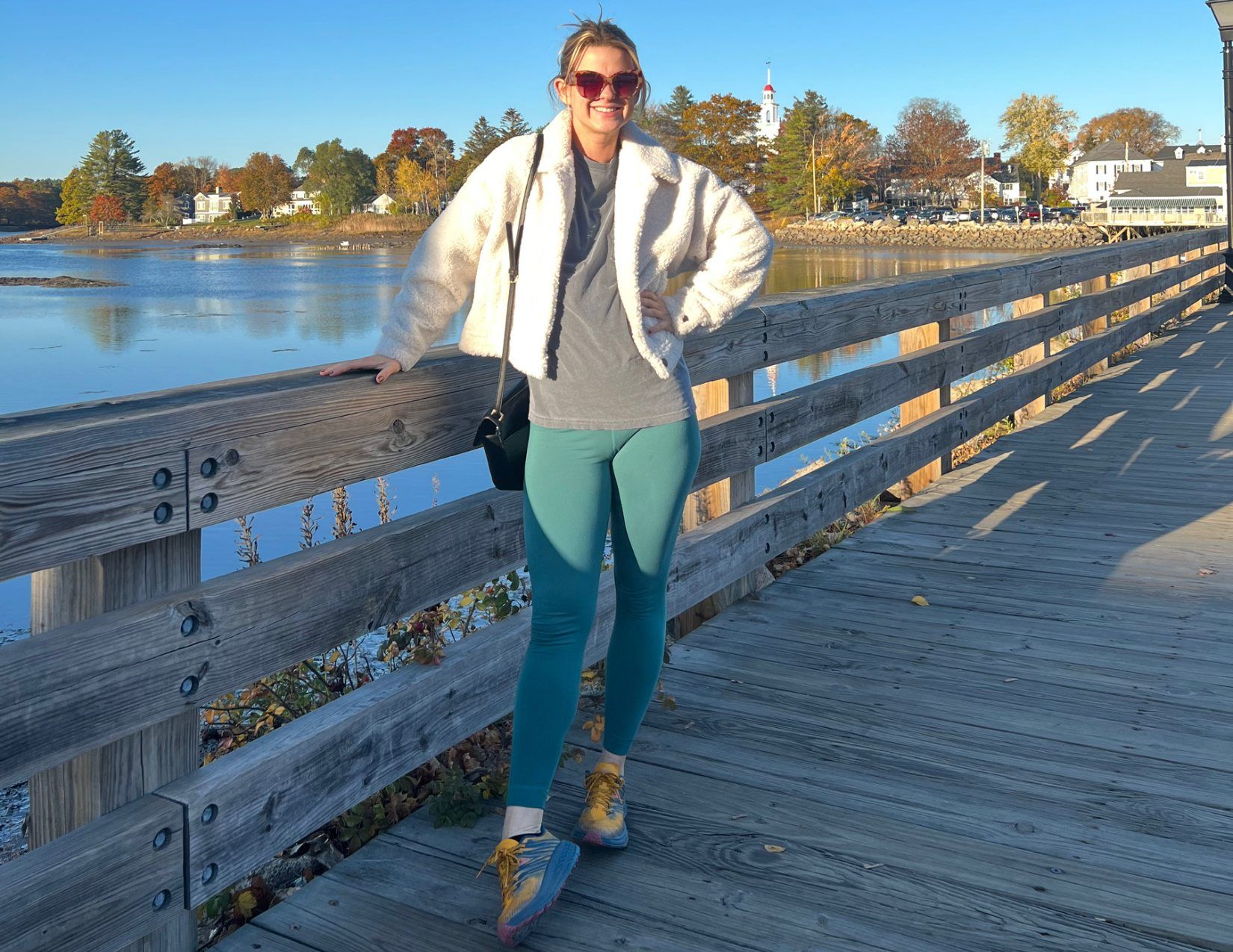 Woman smiling during golden hour on an old and rustic bridge over a lake in Kennebunkport, Maine