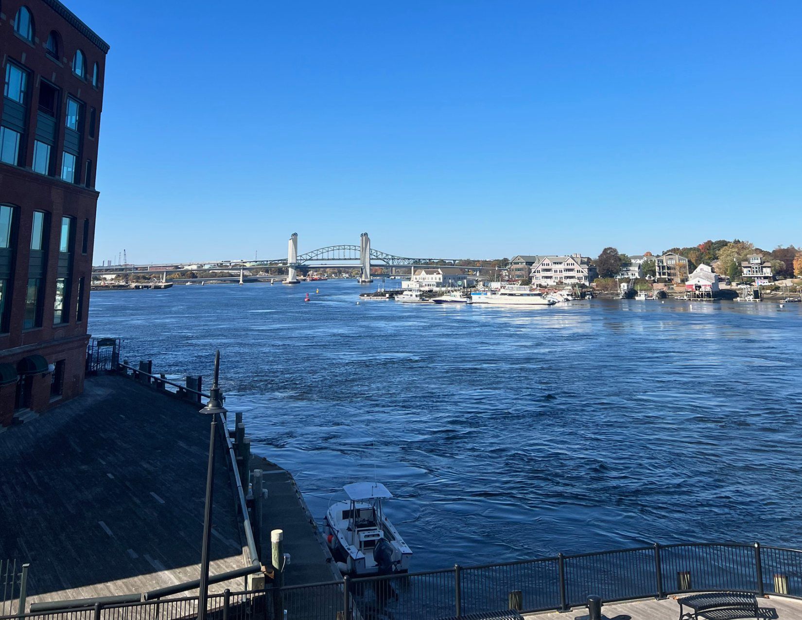 Calm deep blue waters on the Piscataqua River with colonial style homes in the distance and a view of Maine from the Memorial Bridge in Portsmouth, New Hampshire