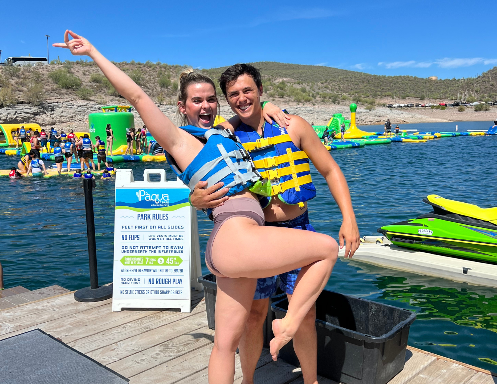 Lacy Cain Baranack and her husband posing in front of a water obstacle course on Lake Pleasant outside of Phoenix, Arizona