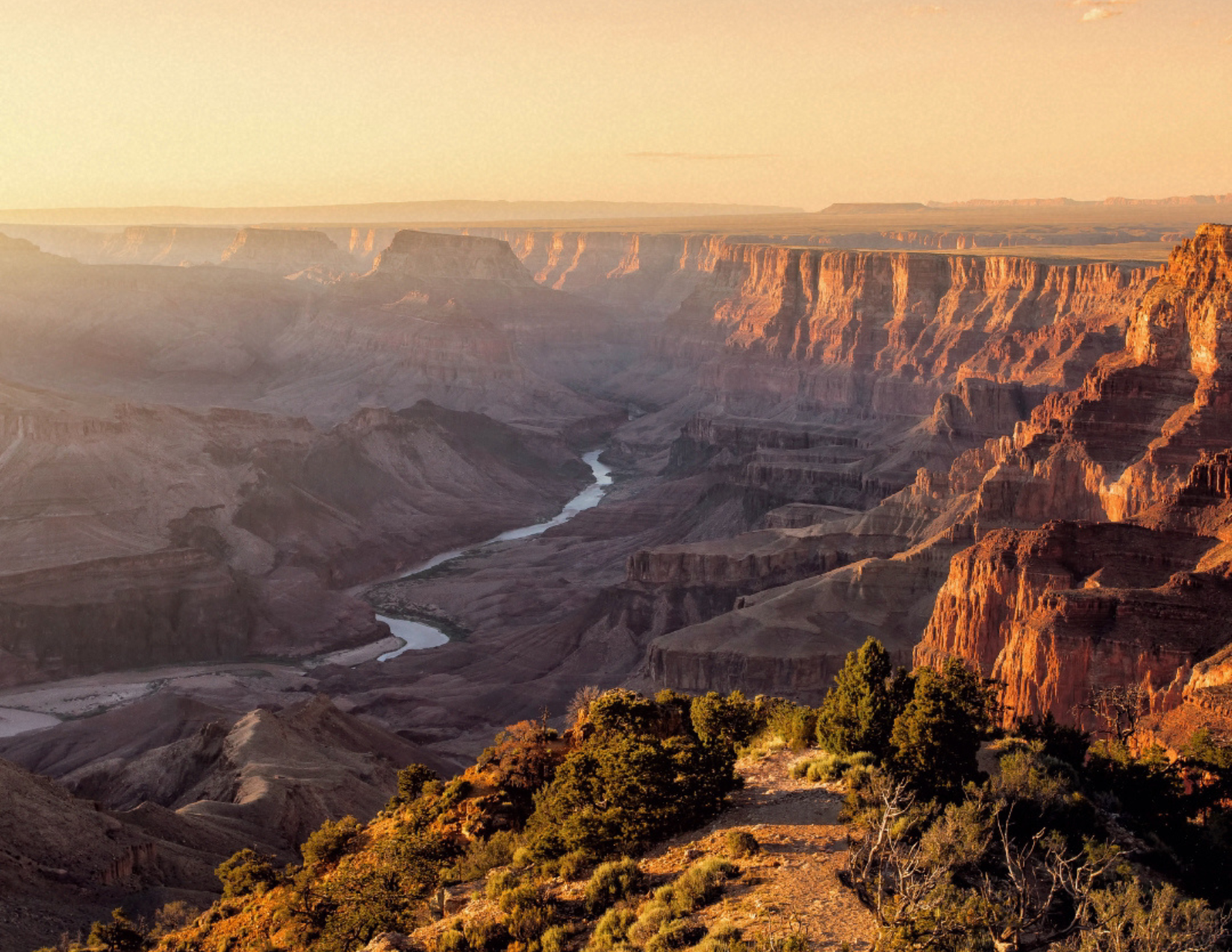 A light orange and hazy sunset at the South Rim of the Grand Canyon in Arizona