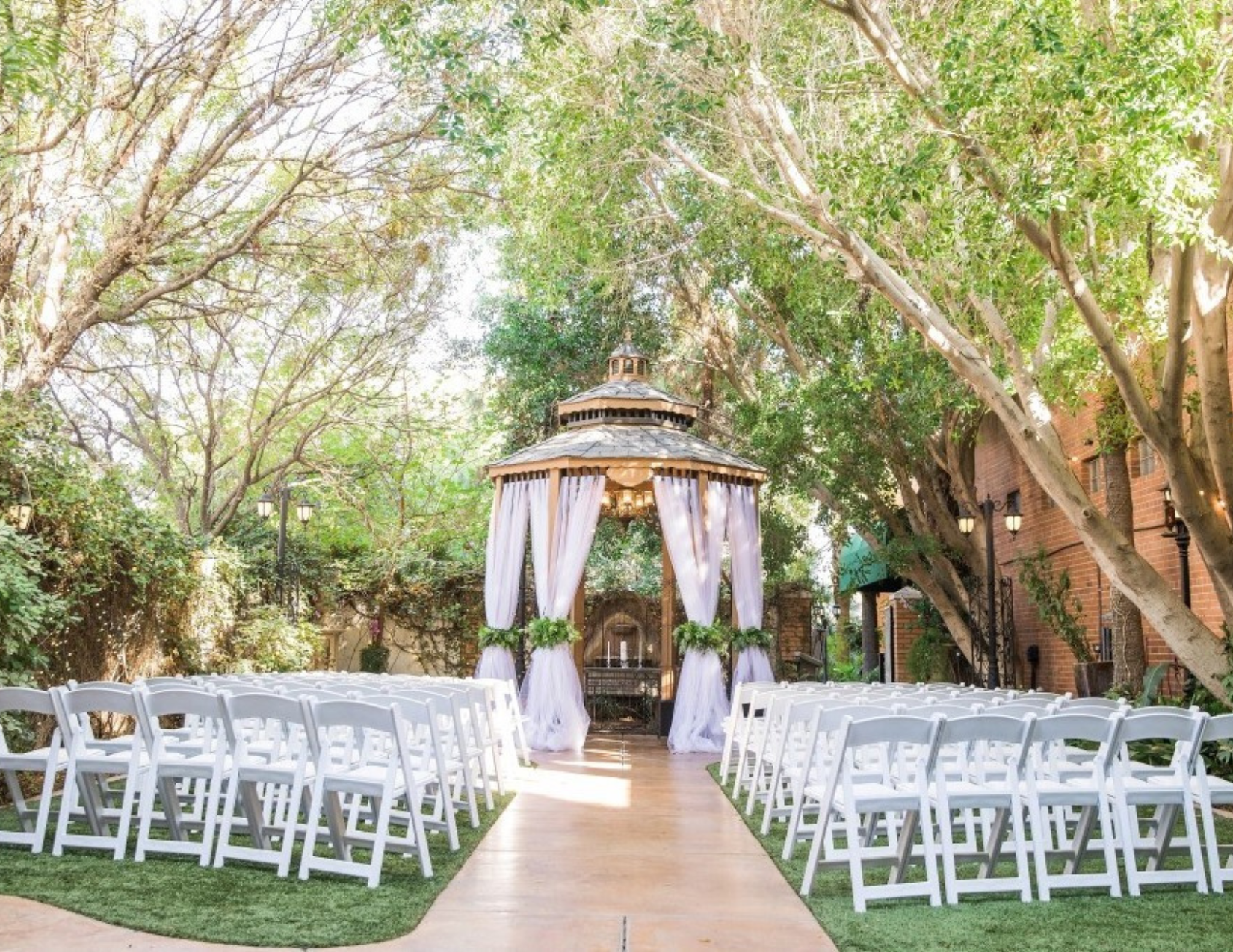 A fairytale like wedding ceremony surrounded by green grass and tall trees in Mesa, Arizona