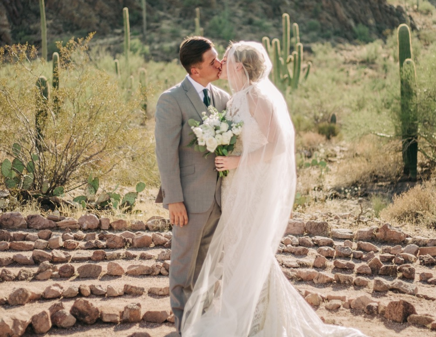 A newly wed couple sharing their first kiss surrounded by beautiful cacti at the Sanctuary Cove venue in Tucson, Arizona