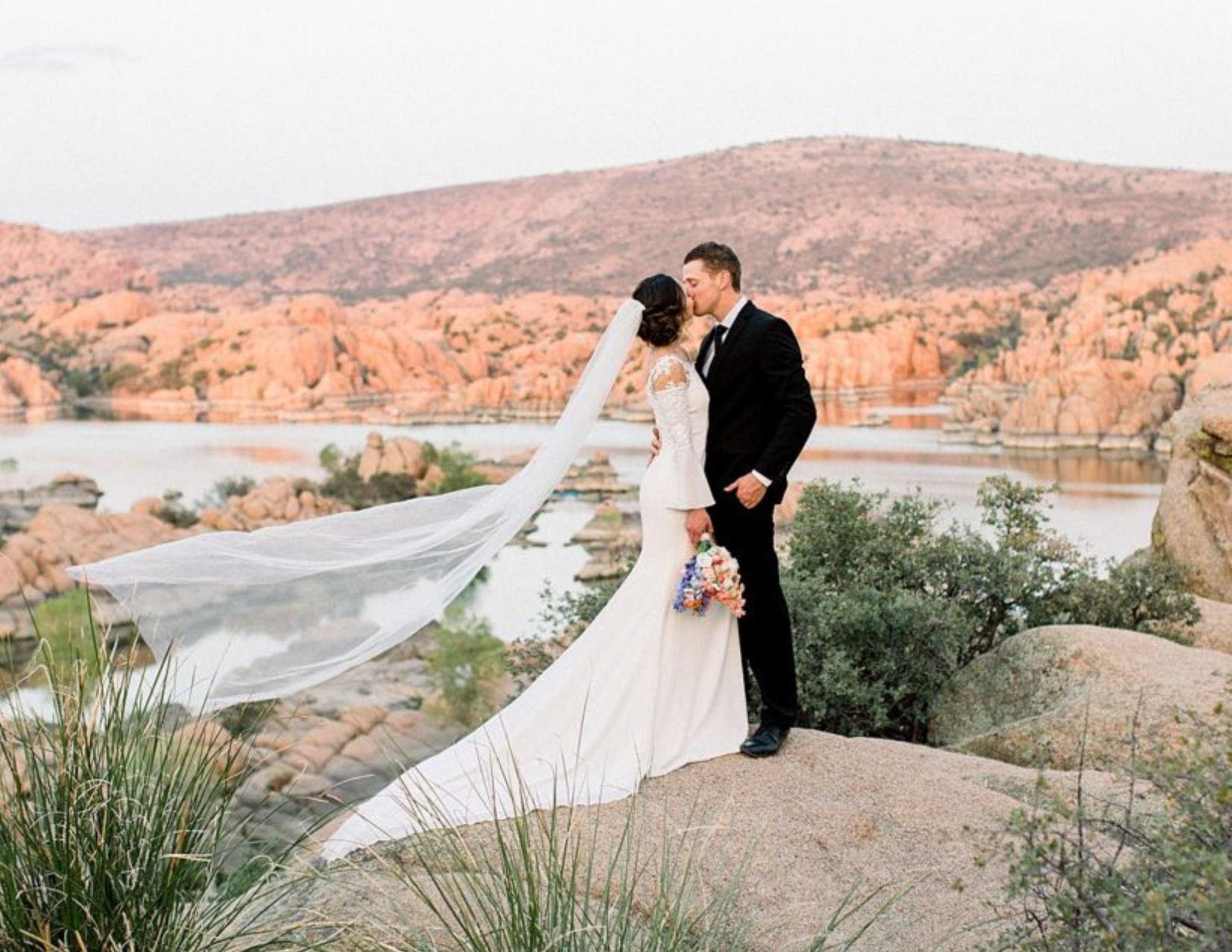 A newly wed couple sharing their first kiss in front of Watson Lake in Prescott, Arizona