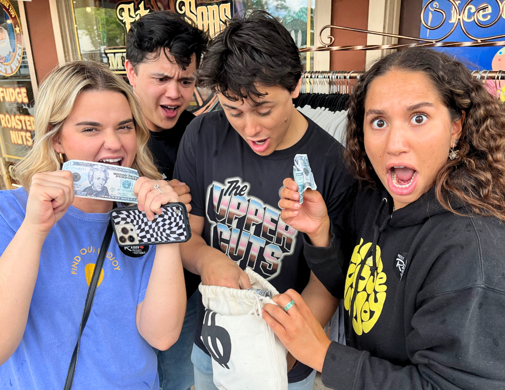 A group of four friends finding money in a bag as they solve clues on an adventure hunt in Prescott, Arizona