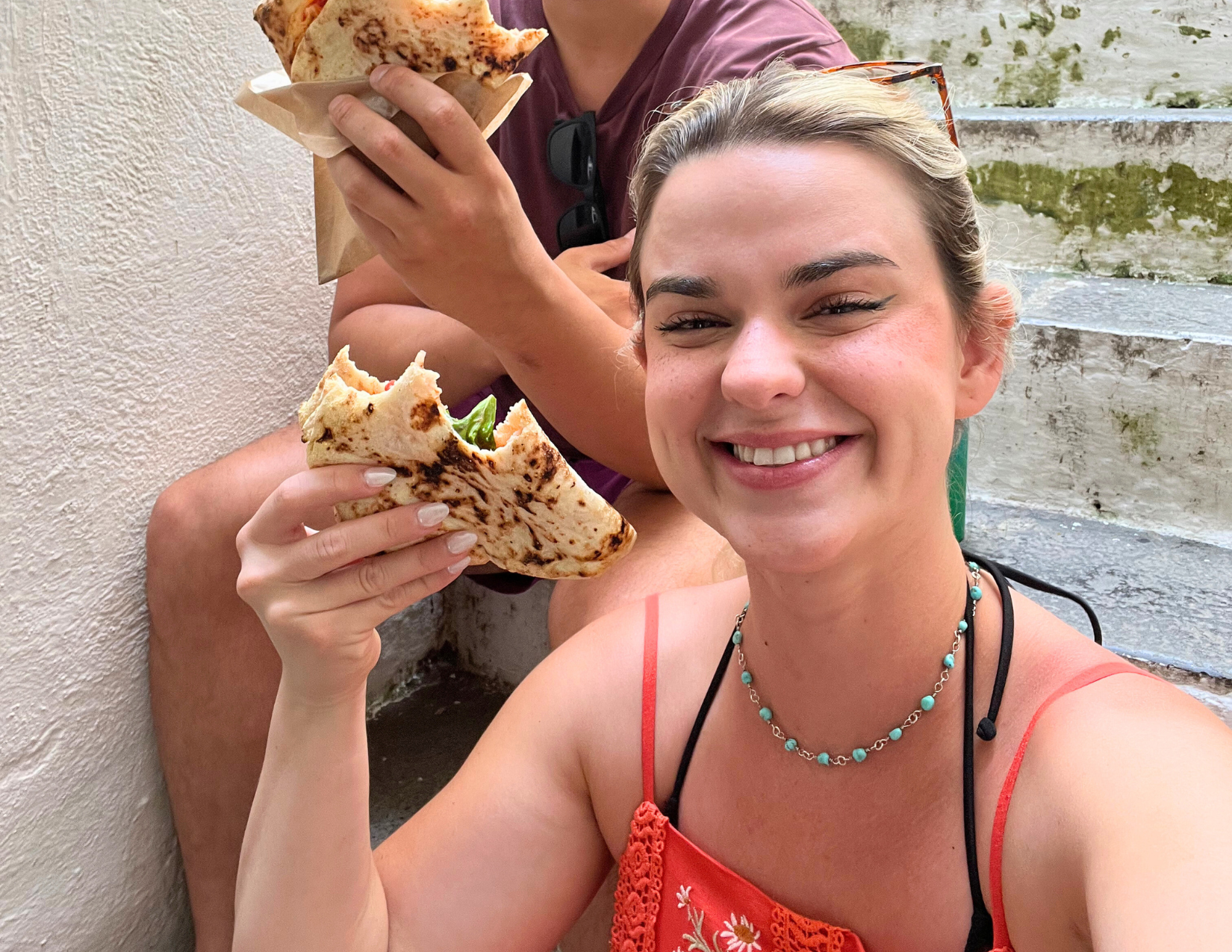 Woman smiling and enjoying a slice of pizza in Amalfi, Italy