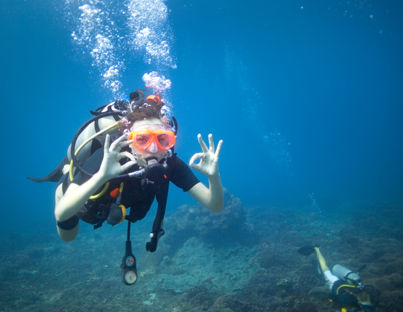 A girl scuba diving in Lake Pleasant, Arizona holding up her hands in excitement
