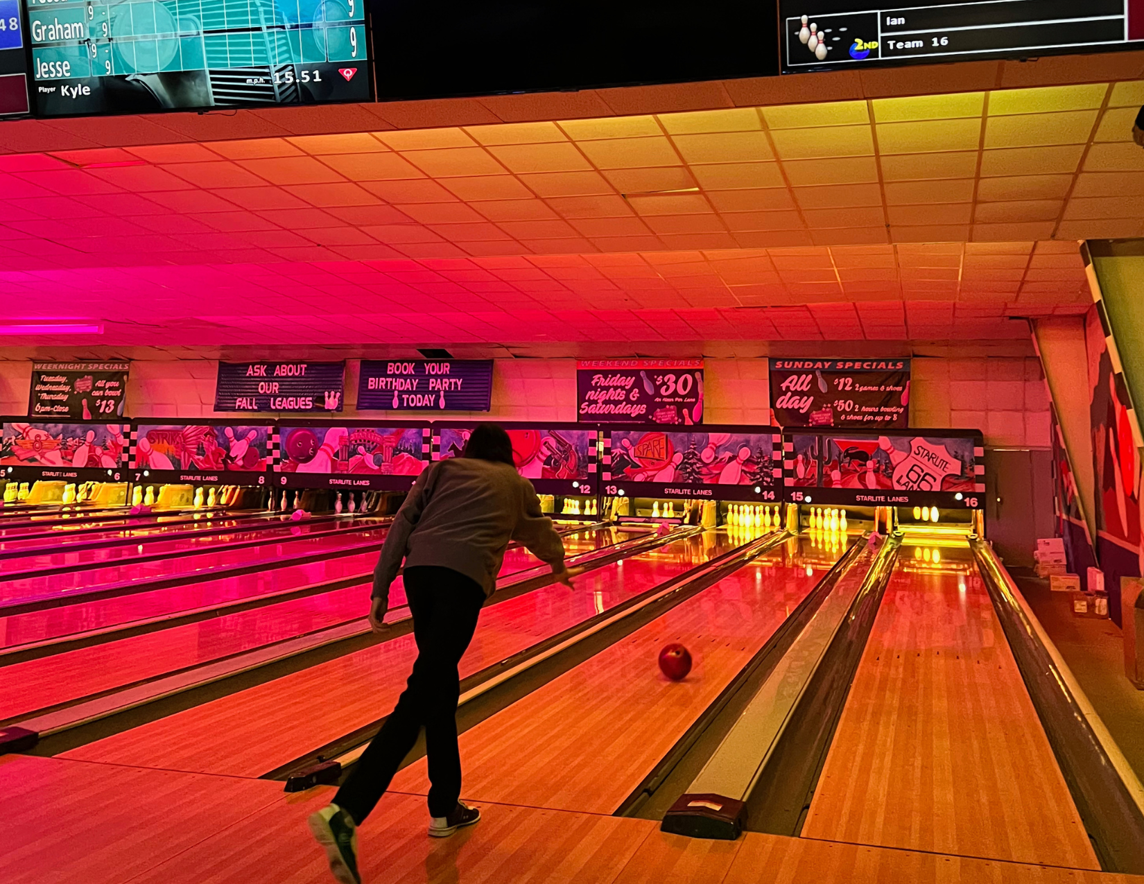 A man bowling a bowling ball in a neon galaxy themed bowling alley in Flagstaff, Arizona