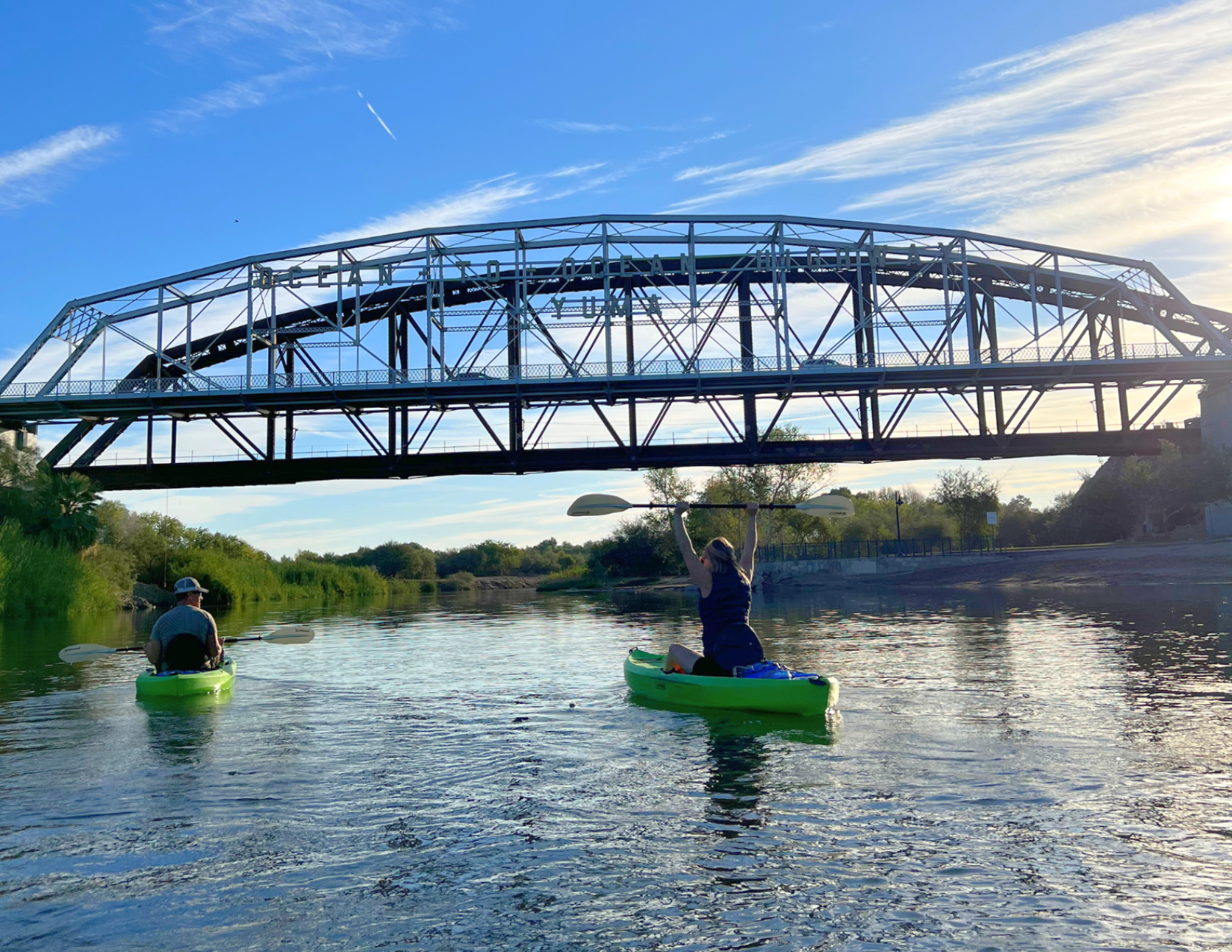 Two people kayaking under the Ocean to Ocean Bridge on the Colorado River in Yuma, Arizona