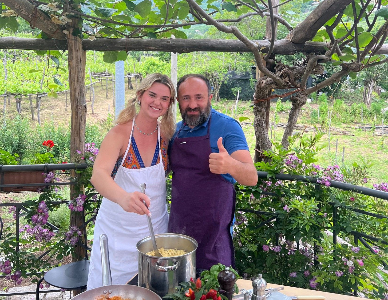 man and woman posing in front of pasta pot in garden on farm in Tramoni, Italy.