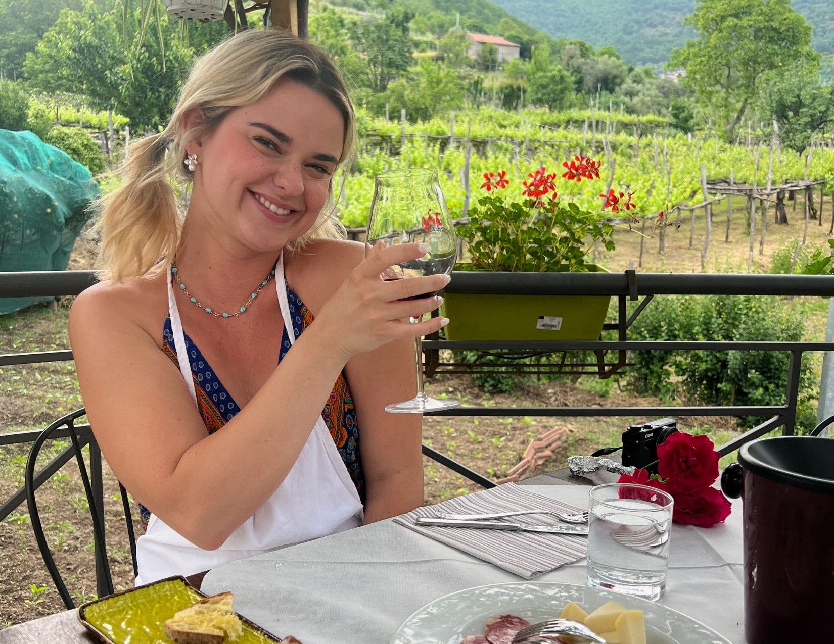 woman holding glass of wine at table with meats and cheeses in Tramonti, Italy