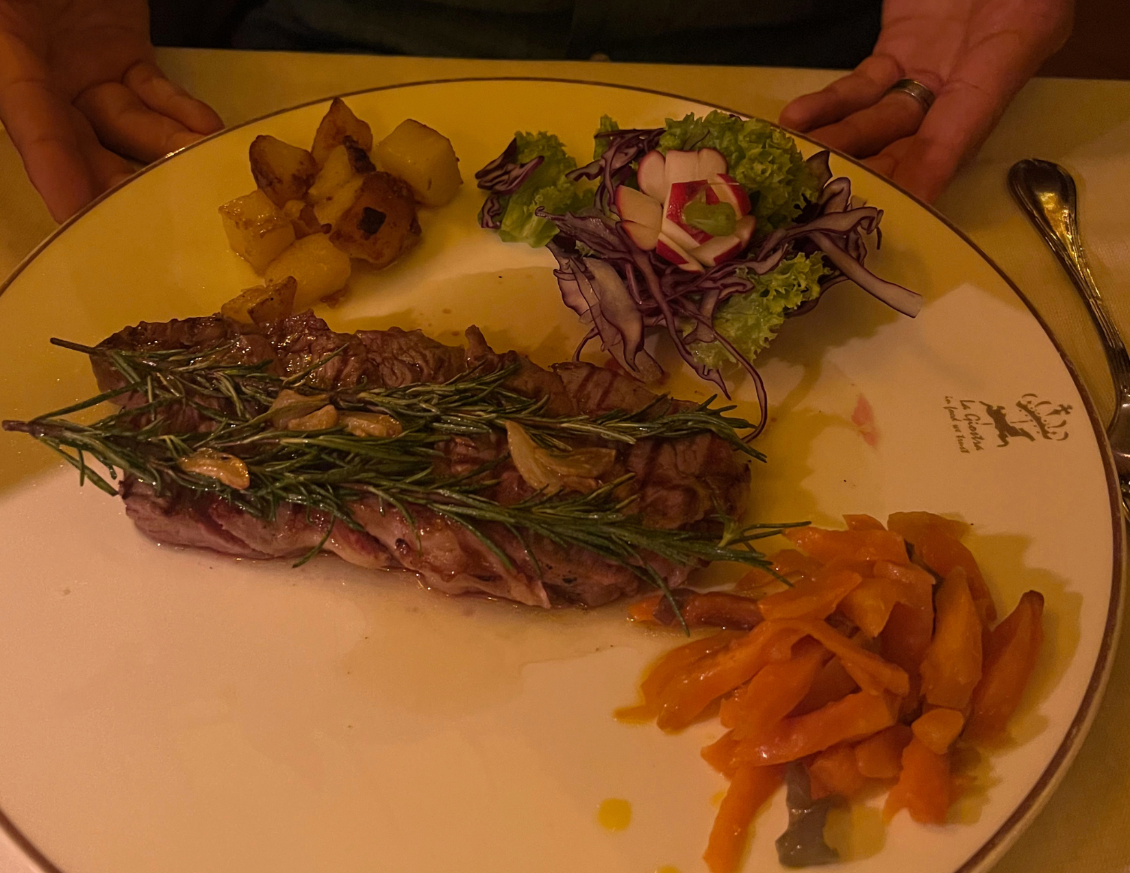 Plate of a large steak garnished with 2 large pieces of rosemary at La Giostra in Florence, Italy