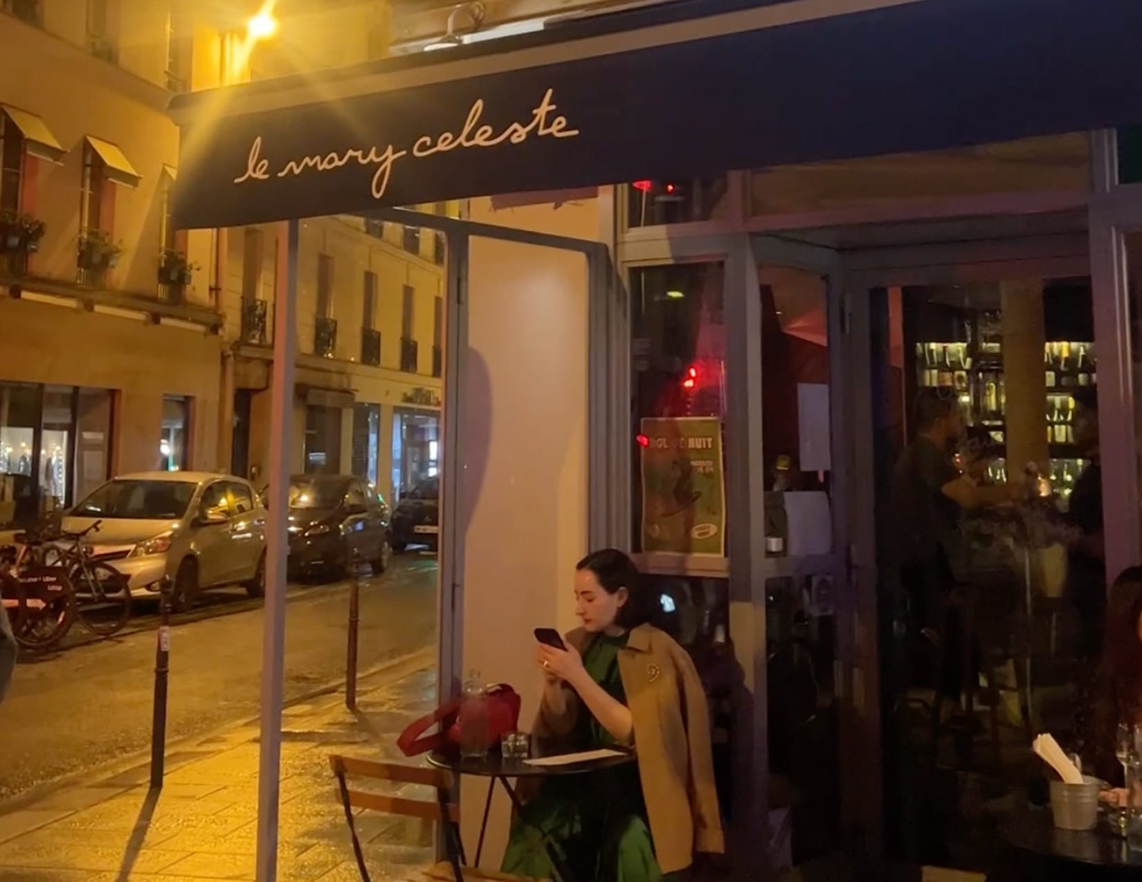 Woman sitting at outside patio in front of Le Mary Celeste in Paris, France