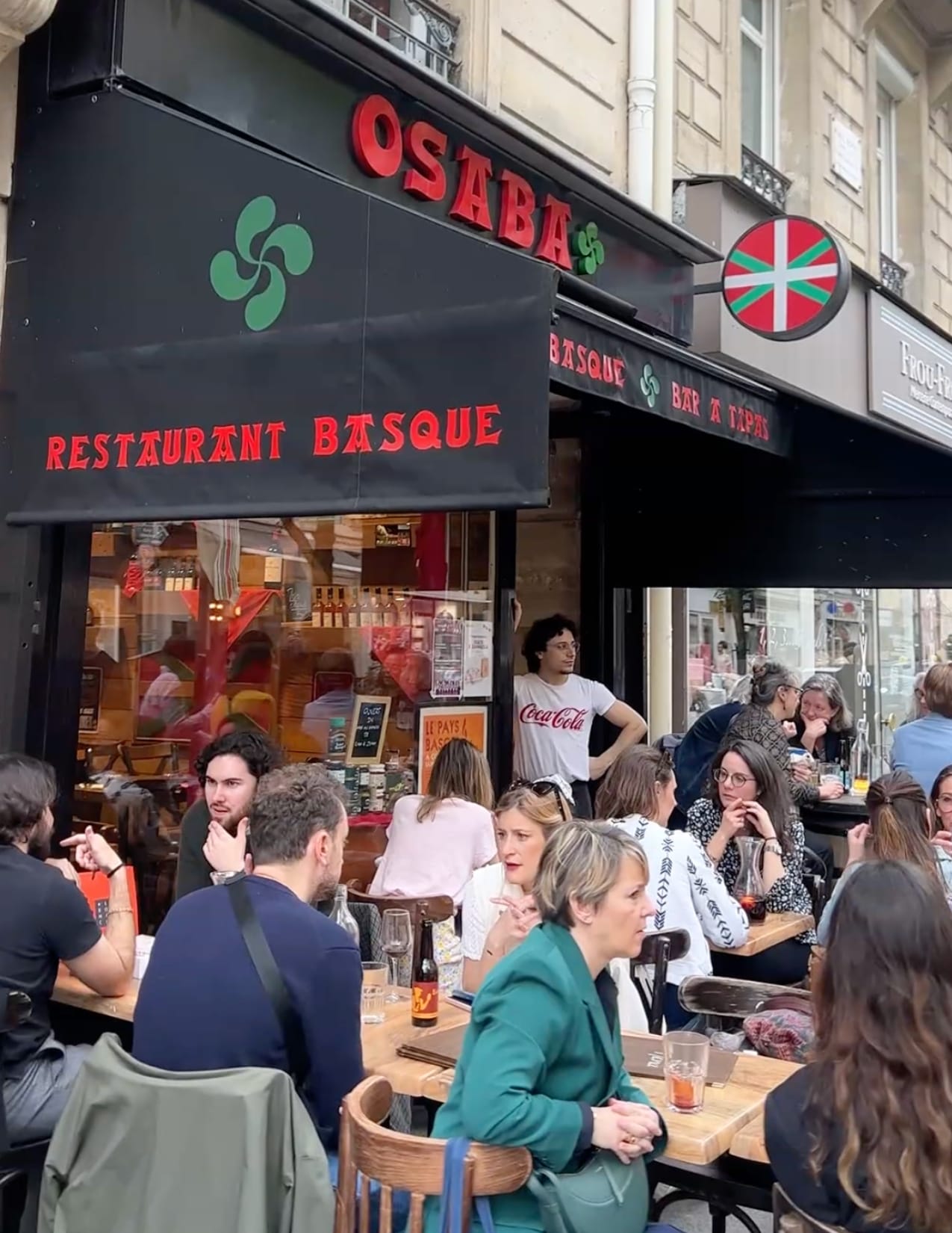 group of people sitting and eating outside of the restaurant Osaba in Paris, France