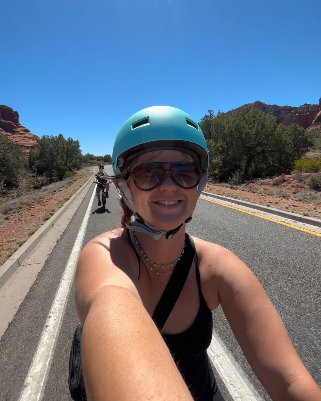 Woman on bike with turquoise helmet smiling on the Red Rock Scenic Byway in Sedona, Arizona